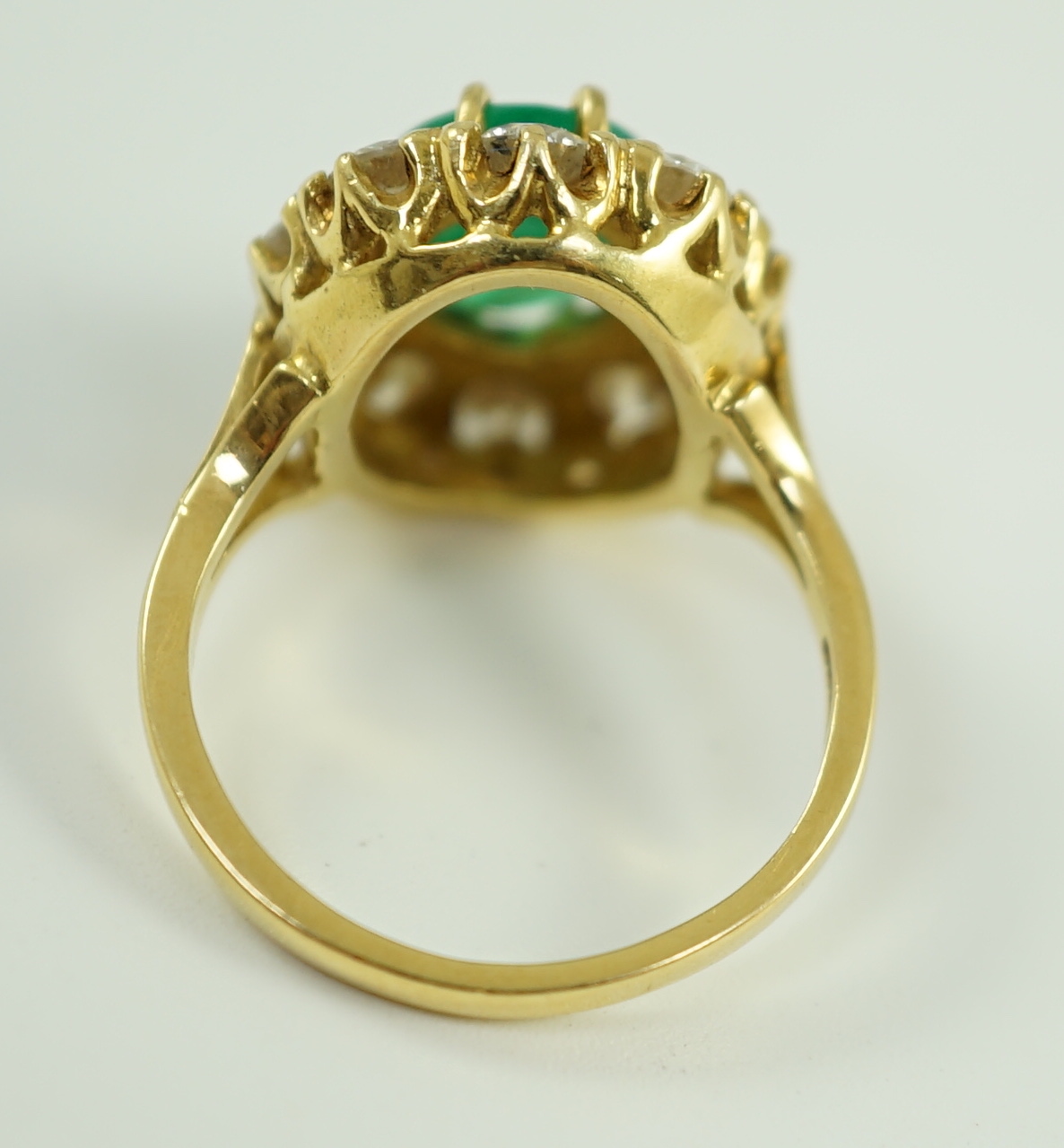 A modern 18ct gold, emerald and diamond set oval cluster ring